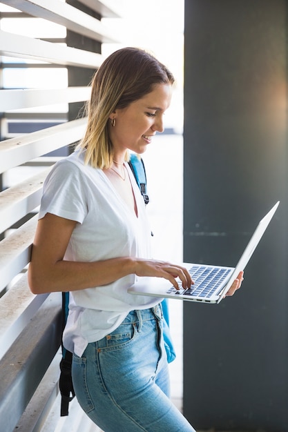 Kostenloses Foto lächelnde frau, die laptop nahe wand verwendet