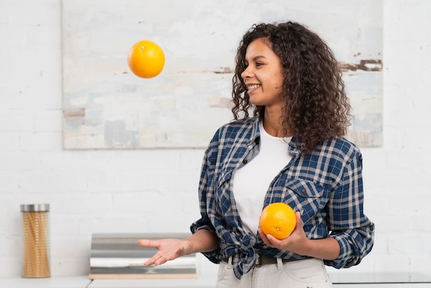 Lächelnde Frau, die mit Orangen jongliert
