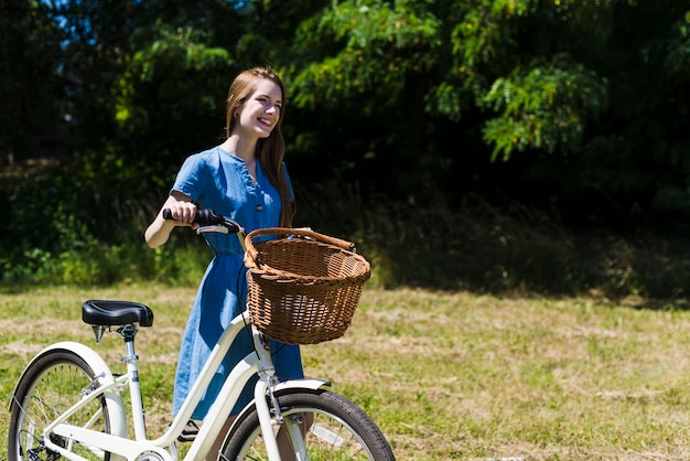 Kostenloses Foto lächelnde frau, die nahe bei ihrem fahrrad geht