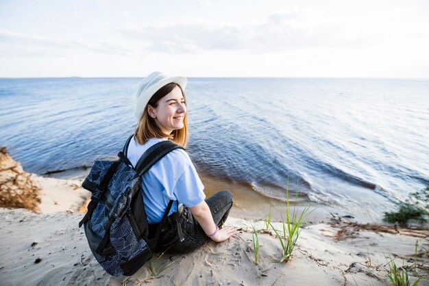 Lächelnde Frau, die nahe Meer sitzt