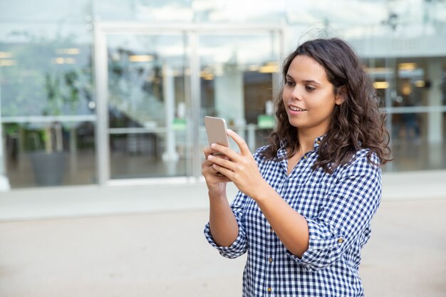 Lächelnde Frau, die Smartphone auf Straße verwendet