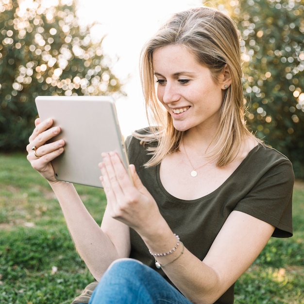 Lächelnde Frau, die Tablette auf dem Boden verwendet