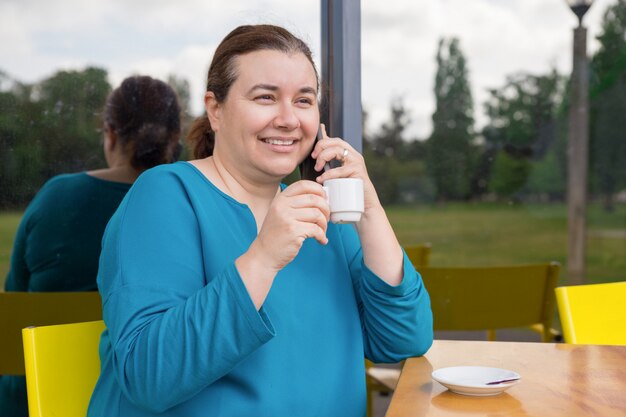 Lächelnde Frau, die Telefongespräch genießt