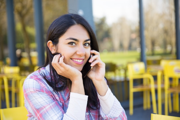 Lächelnde Frau, die um Handy im Café im Freien ersucht