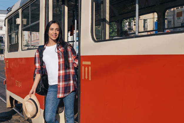 Lächelnde Frau, die von der Tram unten erhält und weg schaut