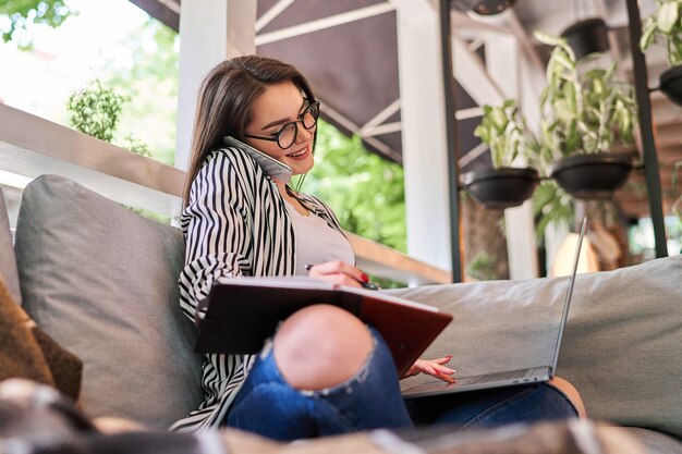 Lächelnde Frau, die zu Hause mit Laptop lernt.