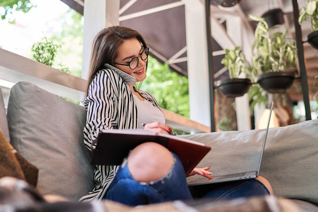 Lächelnde Frau, die zu Hause mit Laptop lernt.