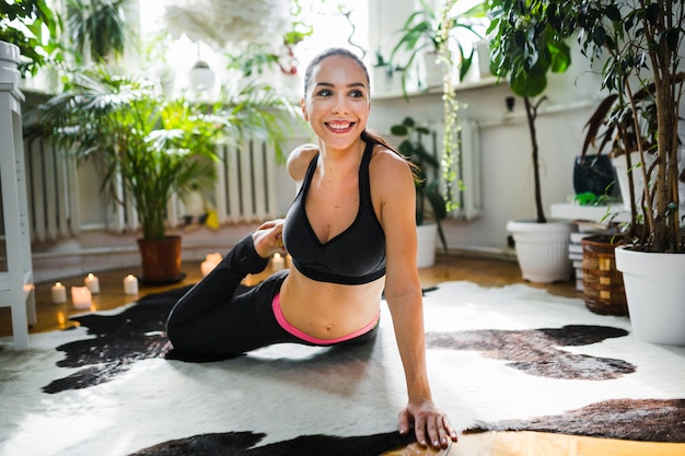 Lächelnde Frau, die zu Hause Yoga tut