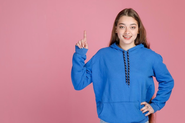 Lächelnde Frau im hellblauen Pullover, die den Zeigefinger nach oben hebt, während sie drinnen eine neue Idee hat