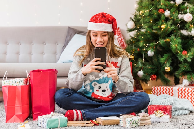 Lächelnde Frau in den Weihnachtshutnachrichten auf Boden