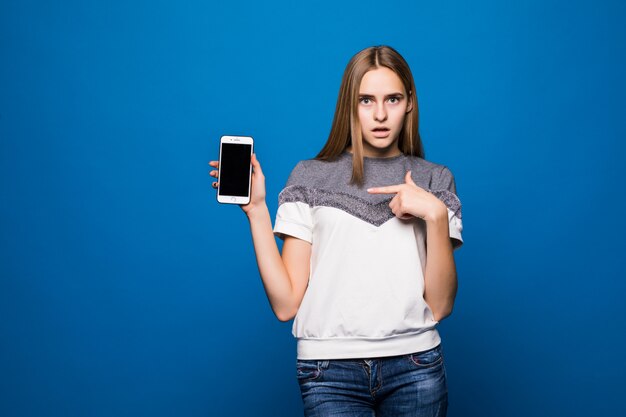 Lächelnde Frau in der Freizeitkleidung unter Verwendung des Smartphones über blauem Hintergrund.