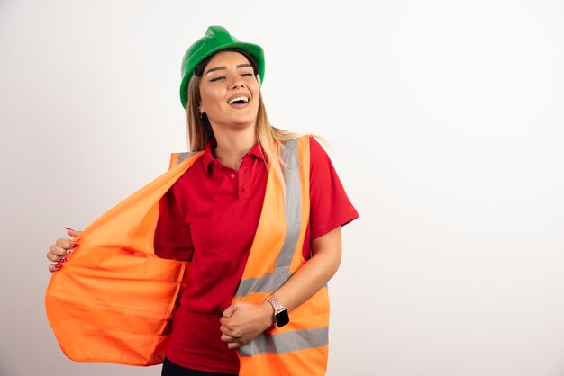 Lächelnde Frau in Schutzuniform und Helm posiert auf weißem Hintergrund.