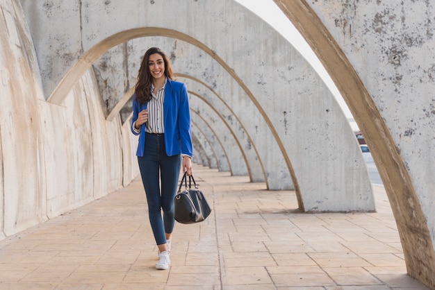 Lächelnde Frau mit blauen Jacke zu Fuß