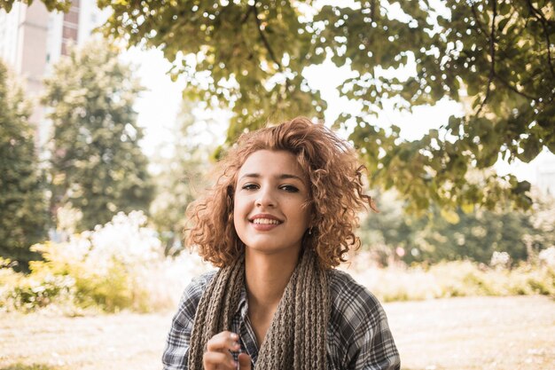 Lächelnde Frau mit dem gewellten Haar im Park