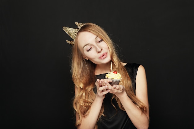 Lächelnde Frau, mit einer Krone, einen Geburtstagskleinen kuchen halten