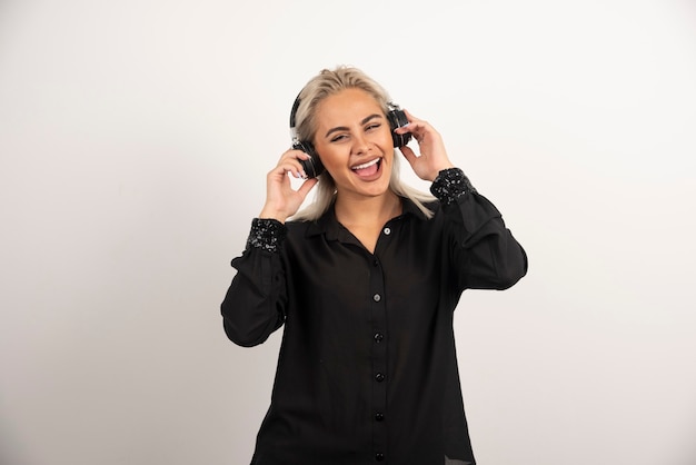 Lächelnde Frau mit Kopfhörern, die auf weißem Hintergrund stehen. Hochwertiges Foto