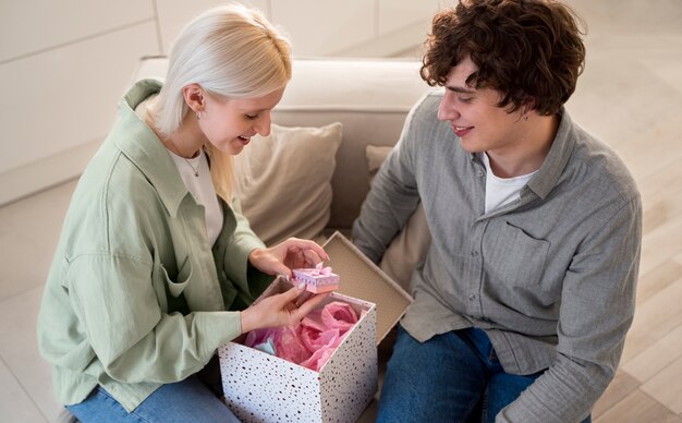 Lächelnde Frau mit mittlerem Schuss, die das Geschenk öffnet