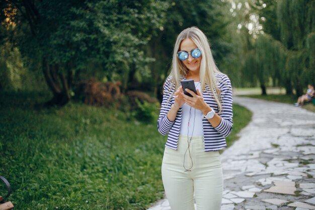 Lächelnde Frau mit Sonnenbrille Tippen auf einem Handy