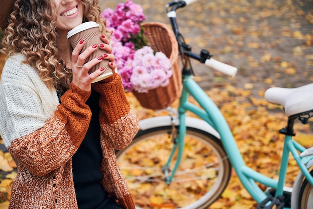 Lächelnde Frau mit Tasse Kaffee oder Tee im Park
