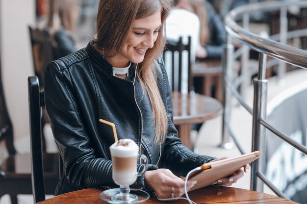 Lächelnde Frau mit weißen Kopfhörern und einen Smoothie auf dem Tisch