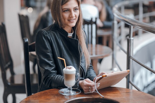 Lächelnde Frau mit weißen Kopfhörern und einen Smoothie auf dem Tisch