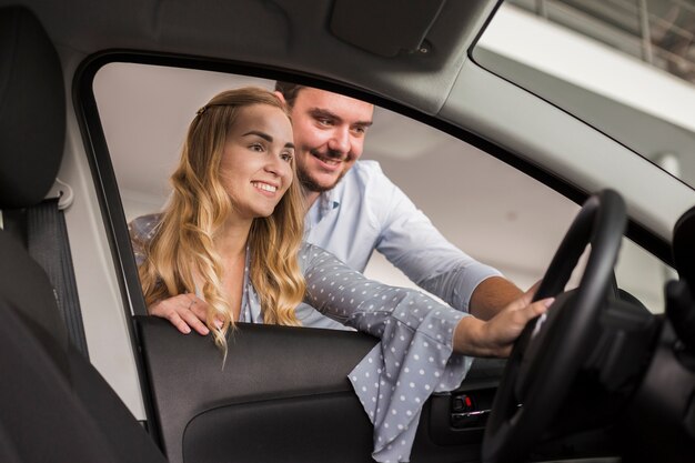 Lächelnde Frau und Mann, die zu einem Auto schauen