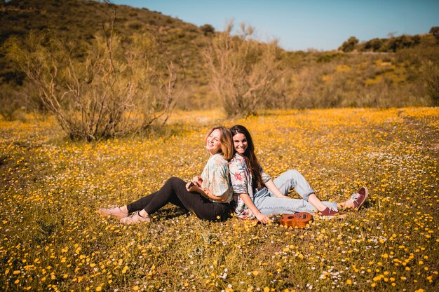 Lächelnde Frauen, die Ukulele auf dem Gebiet spielen