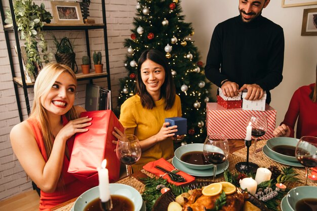 Lächelnde Frauen mit Geschenken am Weihnachtsessen