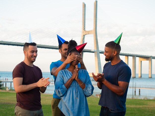 Lächelnde Freunde, die Überraschung für fokussierte Frau machen