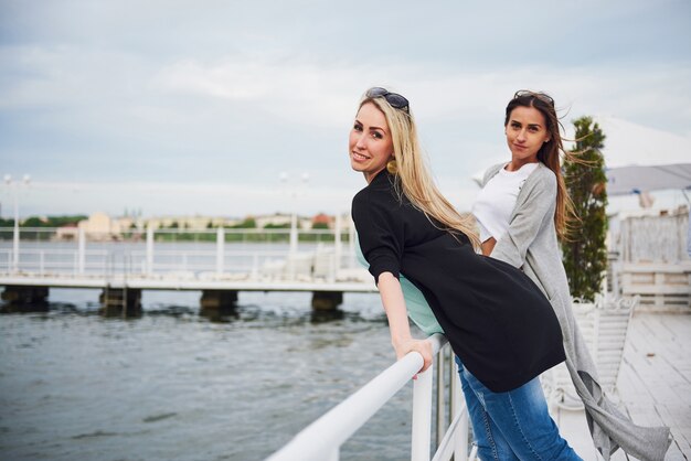 Lächelnde Freunde, die draußen auf dem Strandpier posieren.