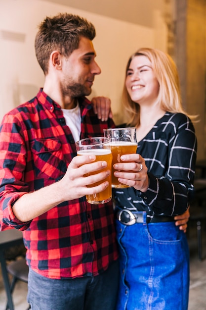 Lächelnde Freunde, welche die Biergläser betrachten einander rösten