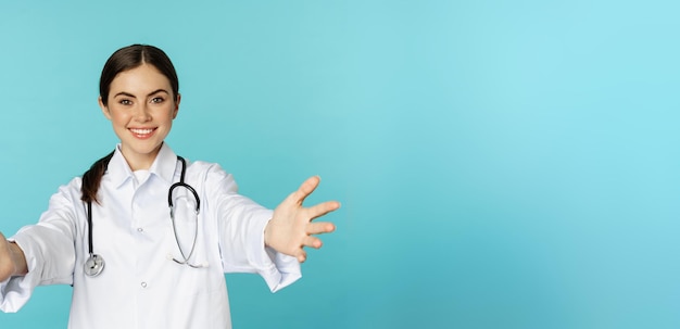 Lächelnde, freundliche Ärztin, Praktikantin im Gesundheitswesen, die Hände erreicht, die zum Umarmen oder Empfangen einladen i