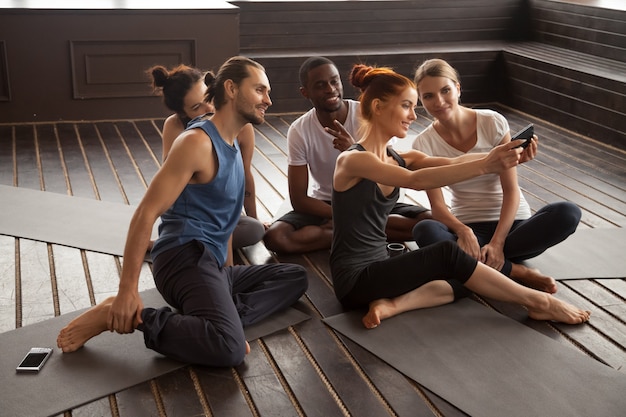 Lächelnde gemischtrassige Leute, die selfie auf Smartphone am Yoga t machen