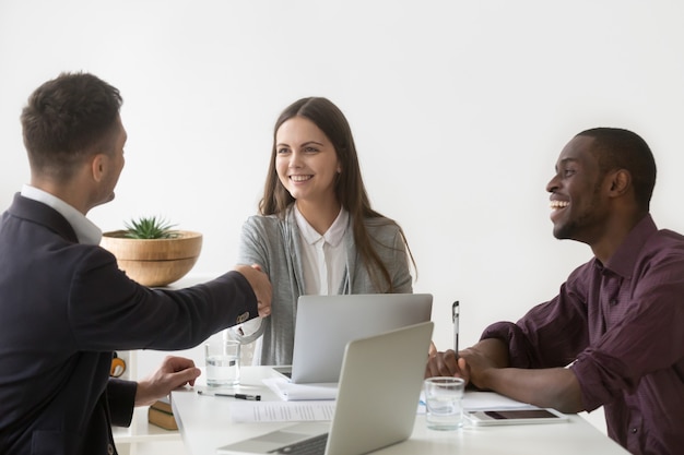 Lächelnde Geschäftsfrau, die Hand des männlichen Partners bei der Gruppensitzung rüttelt