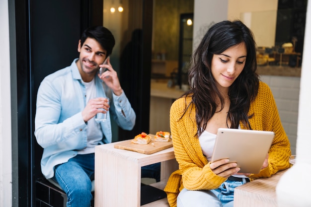 Lächelnde hispanische Frau mit Tablette im Café