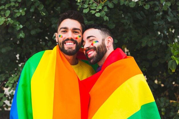Lächelnde homosexuelle Paare, die Regenbogenflagge bedecken