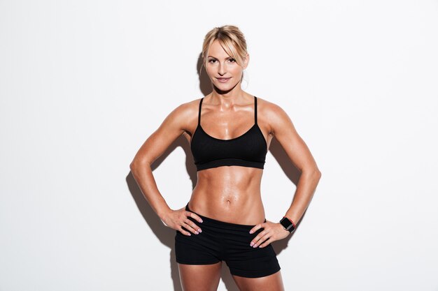 Lächelnde hübsche Athletenfrau, die im Stehen aufwirft