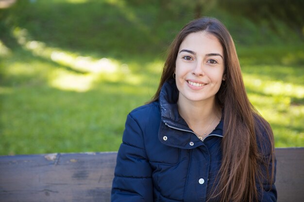 Lächelnde hübsche Frau, die an der Kamera im Park aufwirft