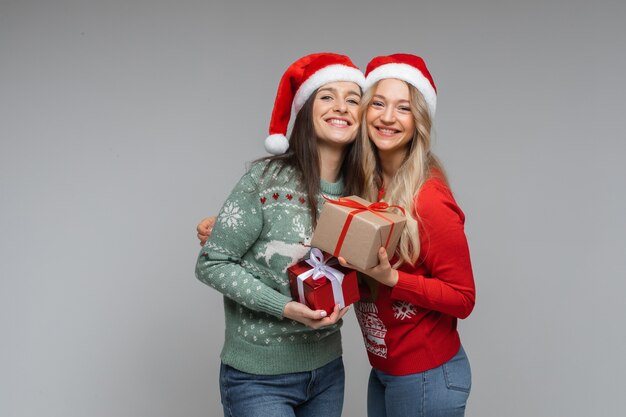 Lächelnde hübsche Freundinnen mit Weihnachtsgeschenken.