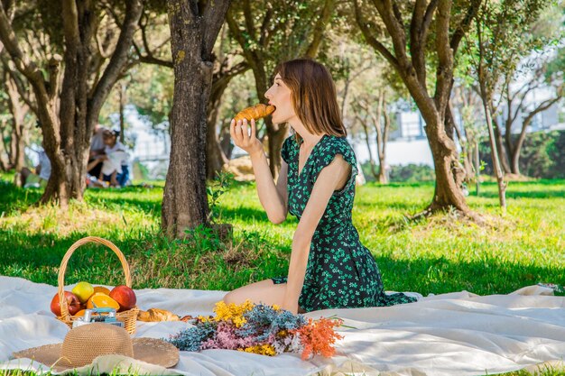 Lächelnde hübsche junge Frau mit Hut auf Picknick im Park