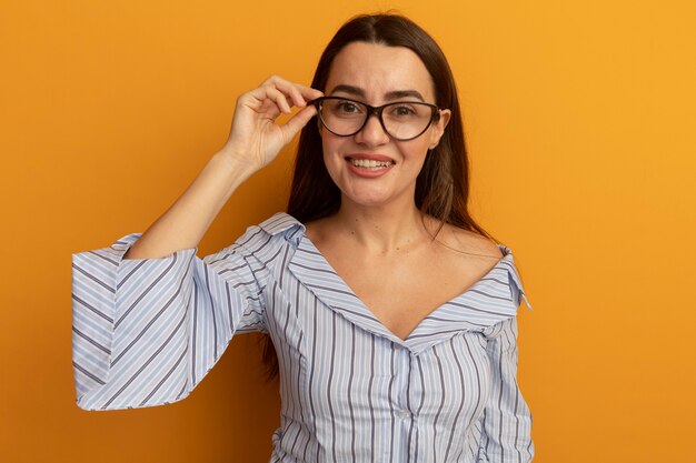 Lächelnde hübsche kaukasische Frau schaut durch optische Brille isoliert