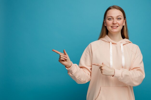 Lächelnde junge blonde Frau, die zur Seite zeigt