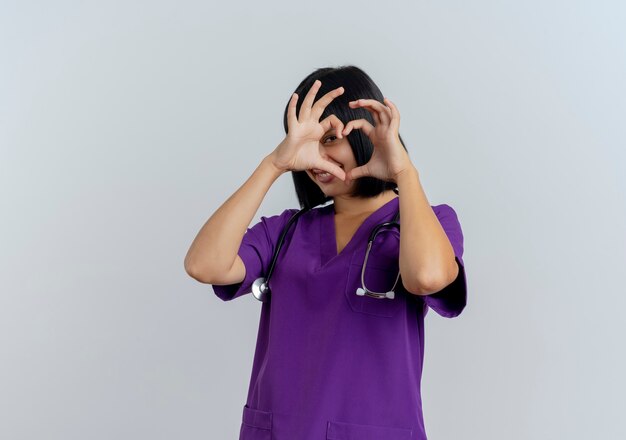 Lächelnde junge brünette Ärztin in Uniform mit Stethoskop