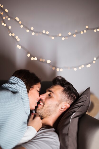 Lächelnde junge Dame, die auf positivem Kerl auf Sofa liegt