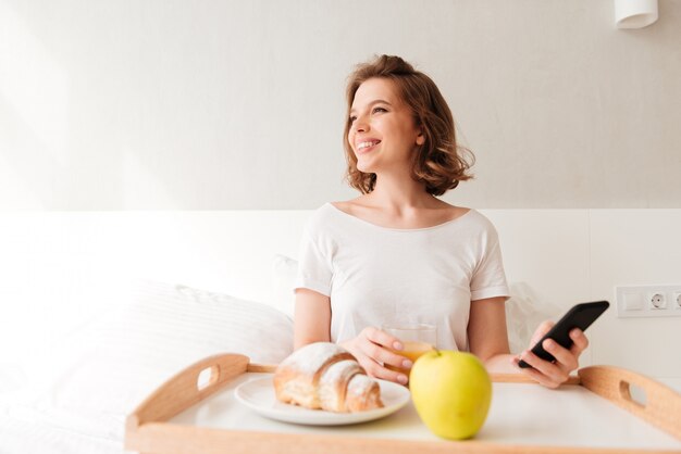 Lächelnde junge Dame, die drinnen sitzt und per Telefon plaudert.