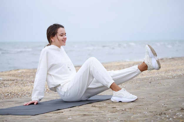 Lächelnde junge Dame, die ihre Meditation am Strand macht Foto in hoher Qualität