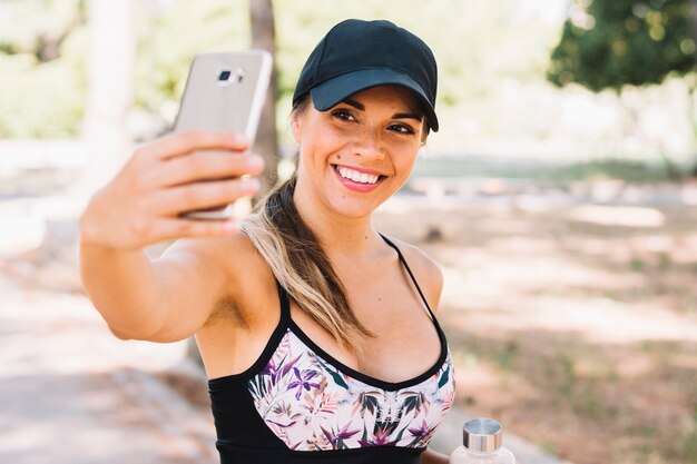 Lächelnde junge Frau der Eignung, die selfie vom Mobiltelefon nimmt