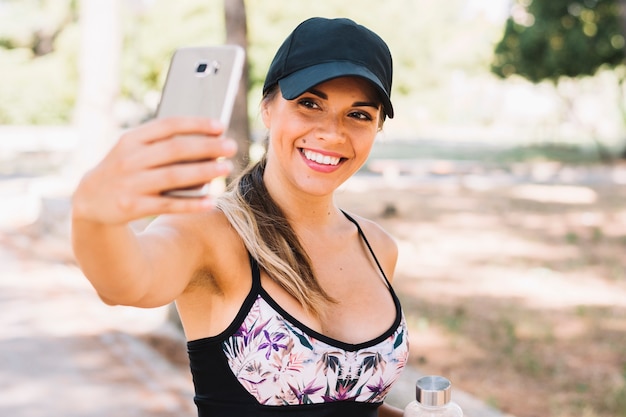 Lächelnde junge Frau der Eignung, die selfie vom Mobiltelefon nimmt