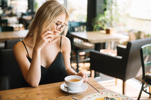 Lächelnde junge Frau, die am Handy im cafÃ? Spricht