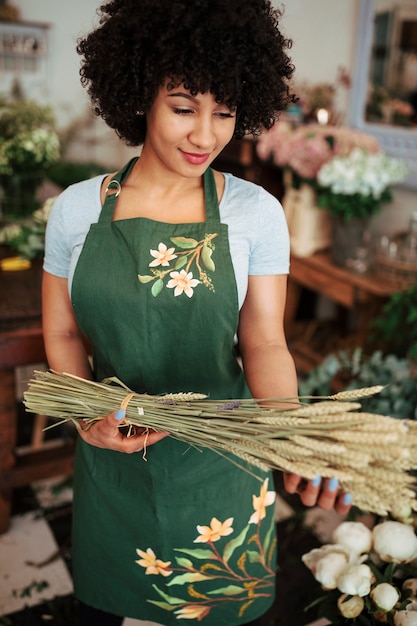 Kostenloses Foto lächelnde junge frau, die auf dem shop hält bündel ährchen steht